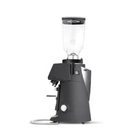 A dark gray electric coffee grinder with a clear hopper on top, shown from a three-quarter angle on a white background.